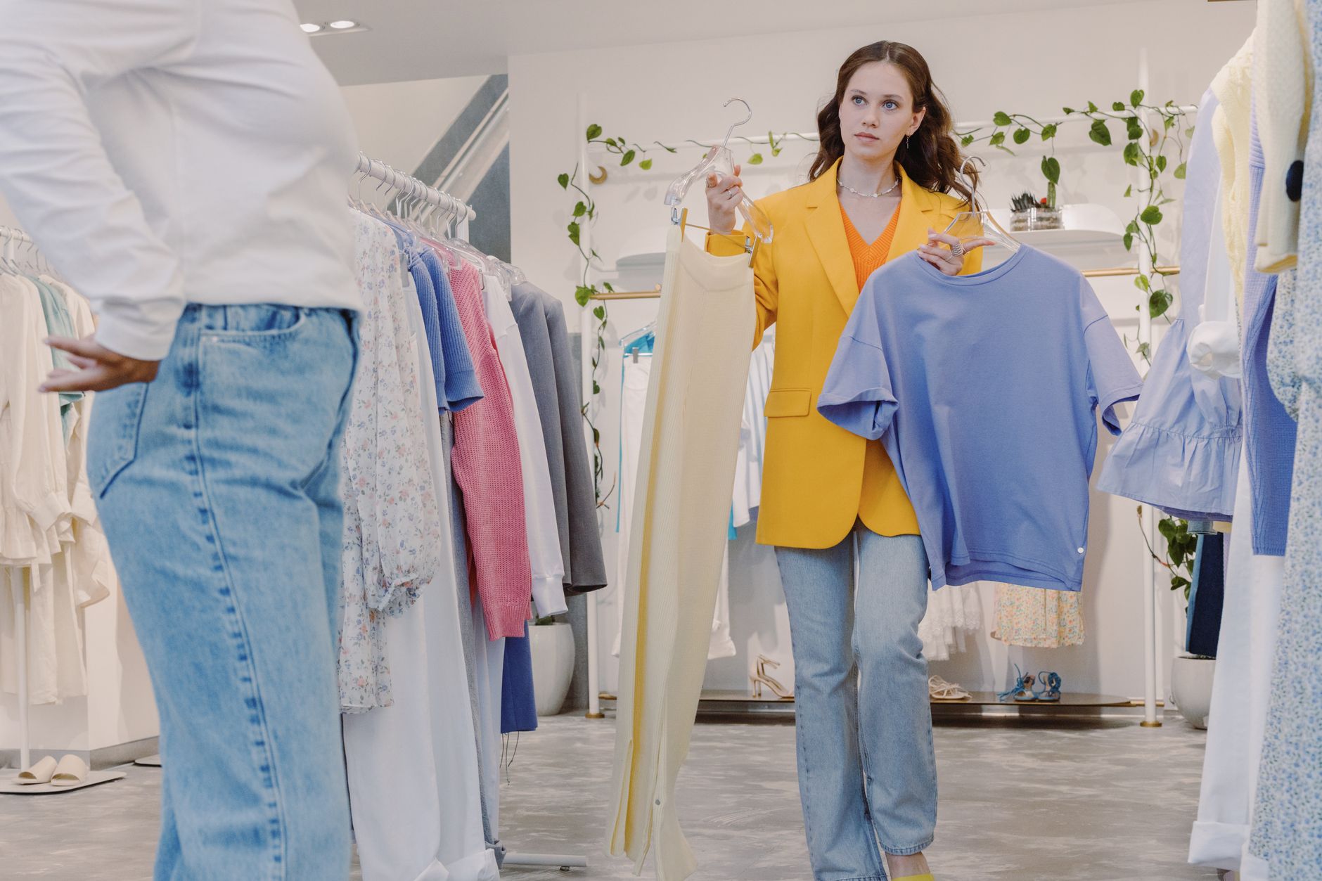 Woman shopping in boutique holding clothes for fitting in a modern fashion store, women's clothing boutique palmyra